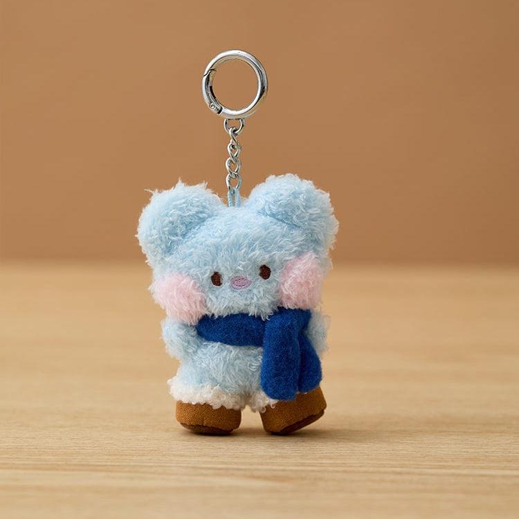 Close-up of a blue plush bear keychain with a blue scarf and pink cheeks.