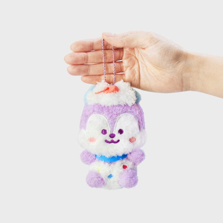 Plush purple and white character keychain with blue collar, held by a hand.