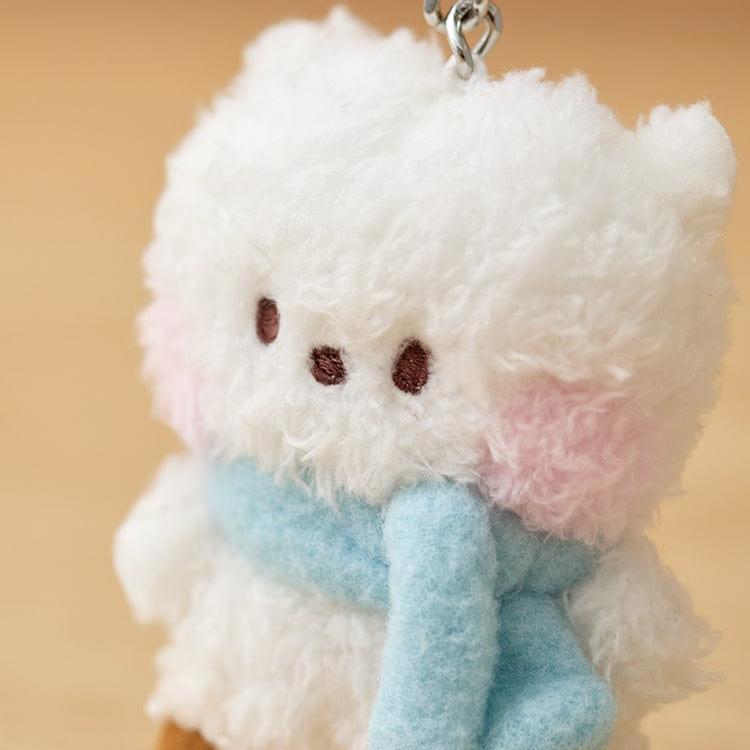 Fluffy white stuffed animal keychain with a light blue scarf and pink cheeks.