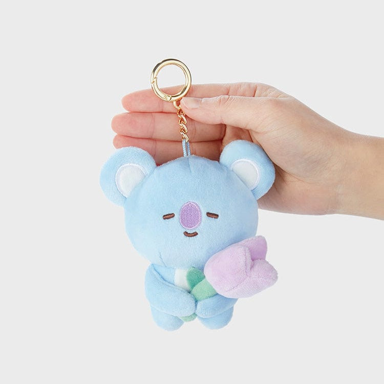 Close-up of a blue plush koala keychain holding a lavender flower.