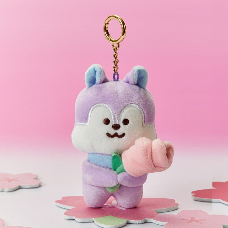 Plush squirrel keychain holding a pink flower, standing on a pink flower-shaped platform, with a pink background.