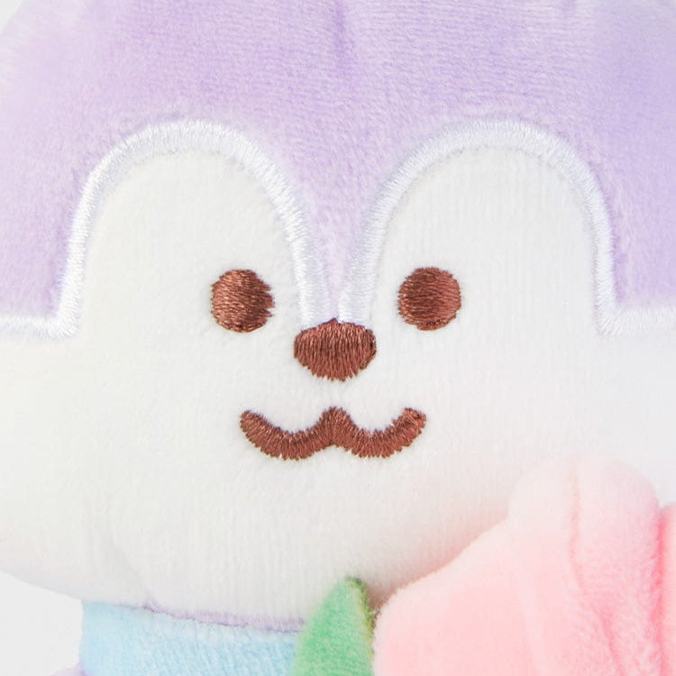 Close-up of a purple and white plush animal toy with brown eyes, nose, and stitched smile.