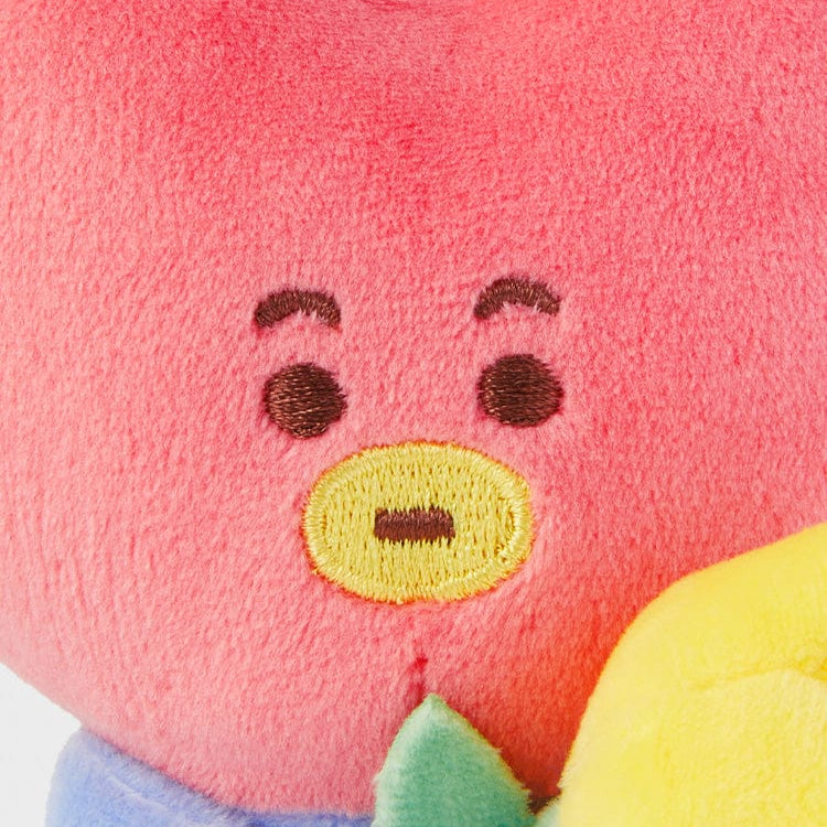 Close-up of a plush toy with a pink face, embroidered eyes, and a yellow outlined mouth.