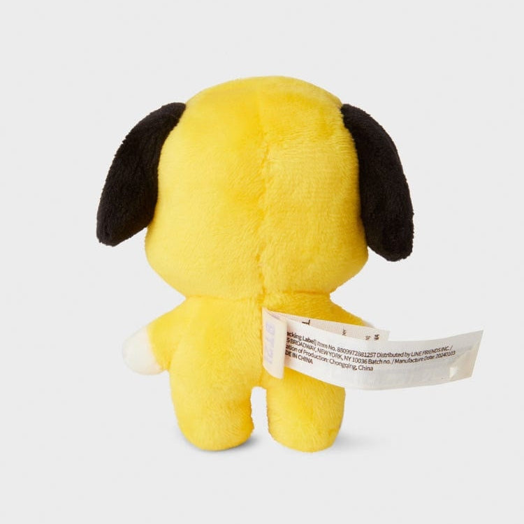 Rear view of a yellow, plush BT21 Chimmy character toy with black ears. The toy has a white tag attached.