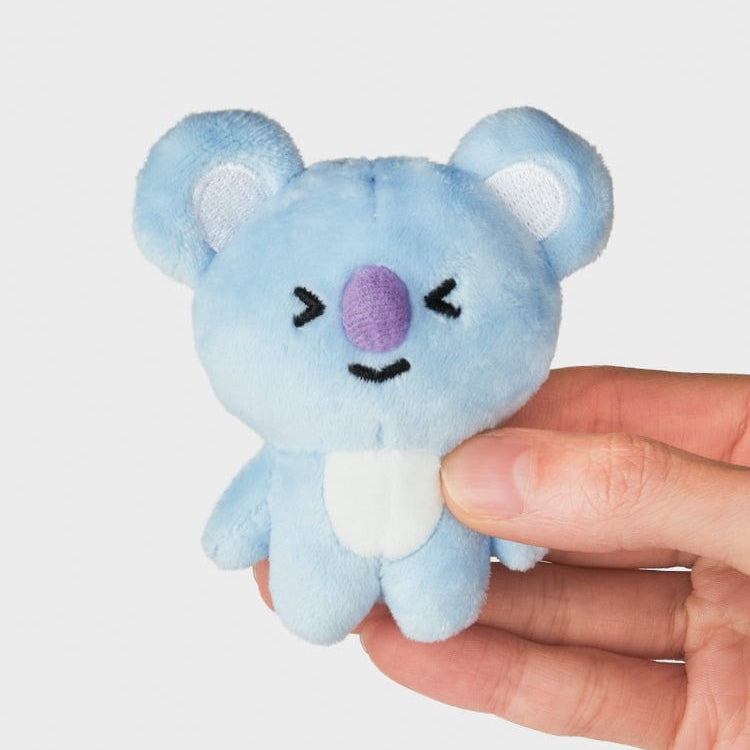 Close-up of a blue koala plush toy with a purple nose, being held by a hand.