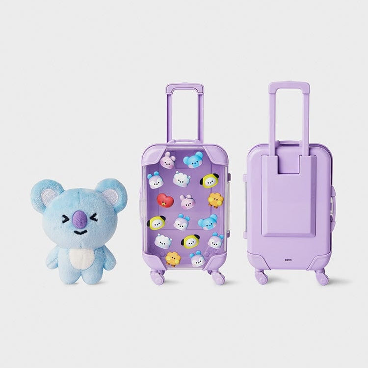 Blue koala plush toy next to two clear purple suitcases.