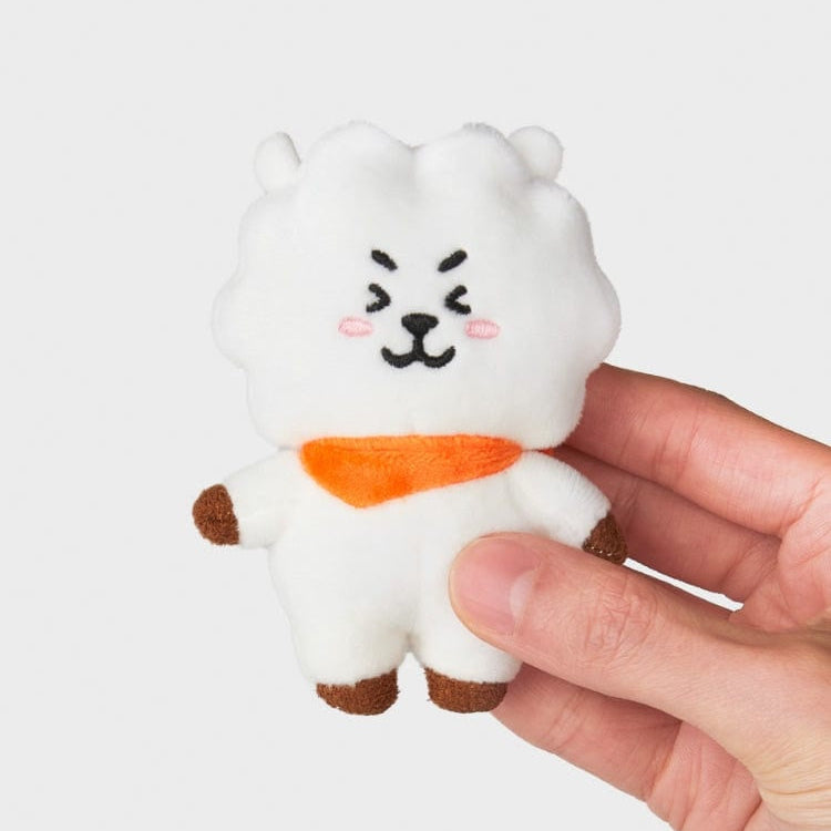 A stuffed white bear toy with an orange scarf held in a hand.