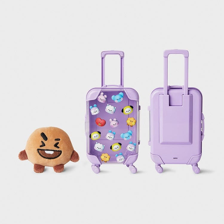 Brown plush toy next to two purple suitcases with cartoon character decorations.