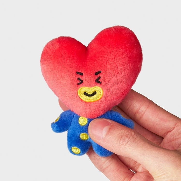 BT21 Tata plush toy in a hand. The plush is red and heart-shaped, wearing a blue outfit with yellow accents.