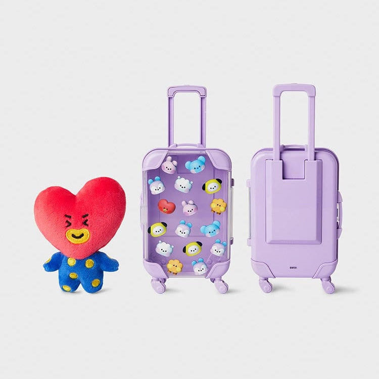 Plush Tata character next to two purple suitcases.