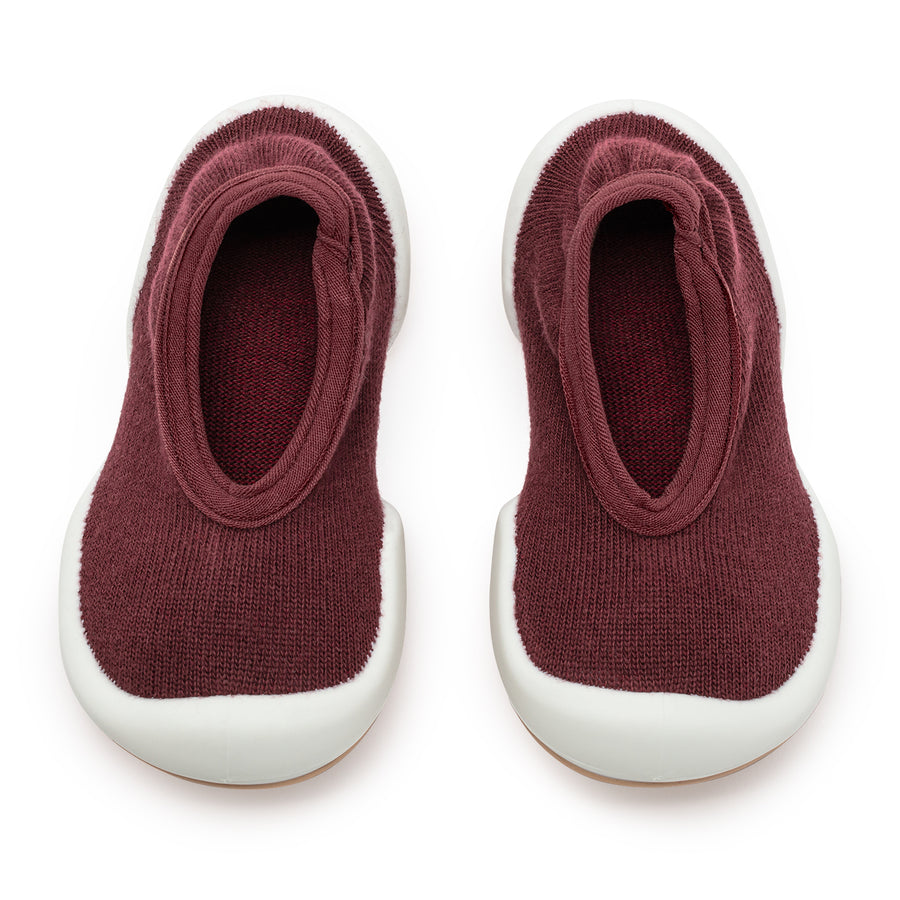 Two maroon knitted shoes with white soles.