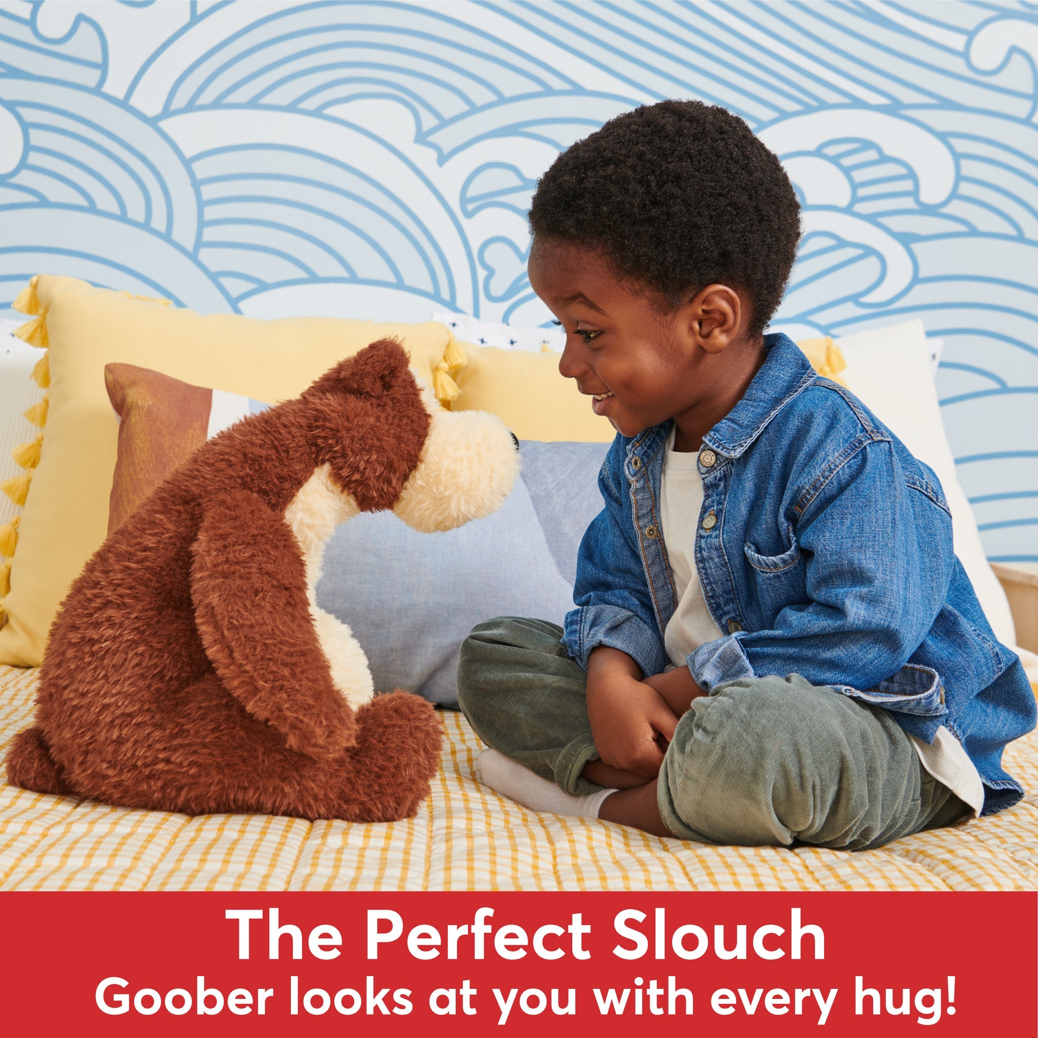 A young boy sits cross-legged looking at a plush dog toy.