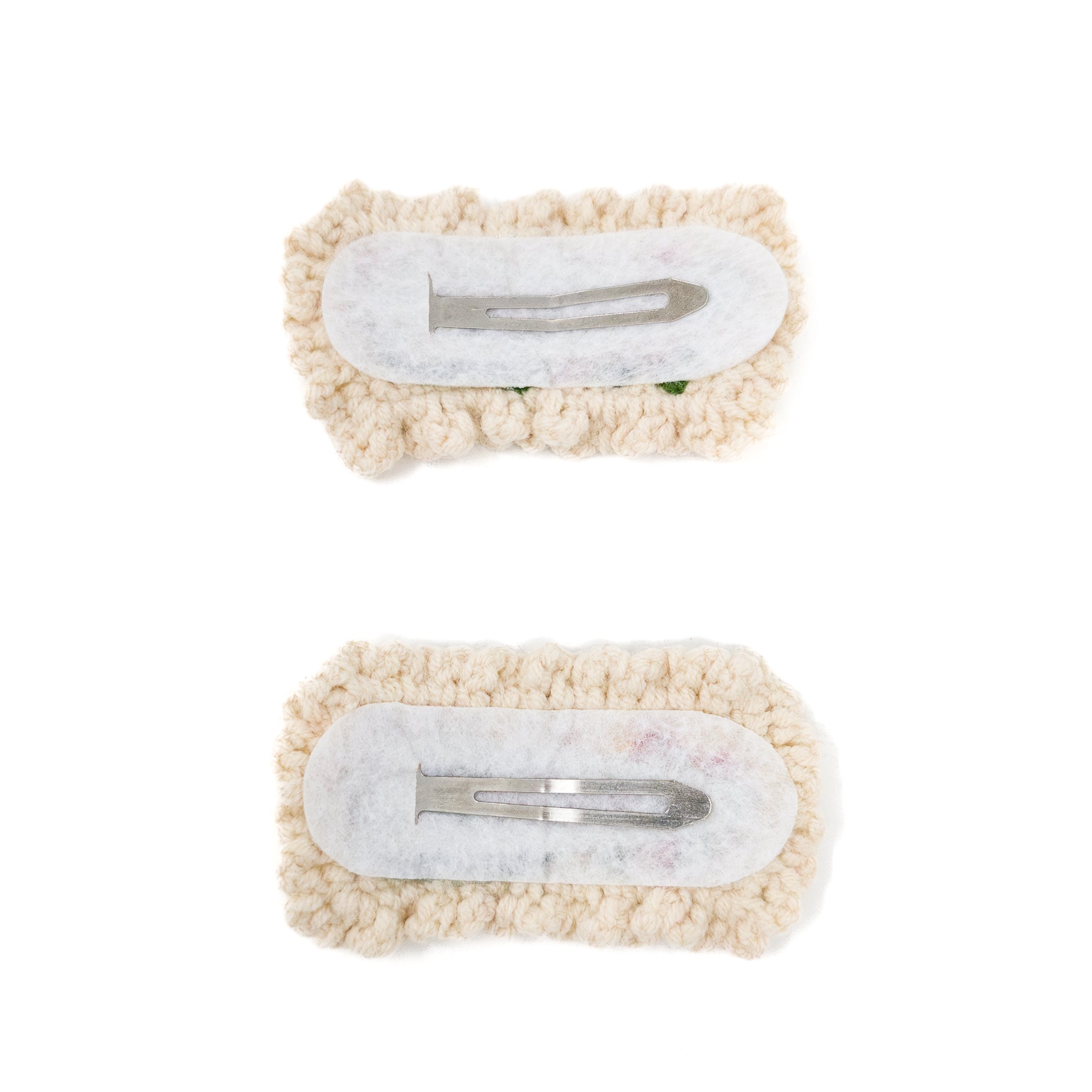 Two knitted hair clips with white fabric and silver clasps.