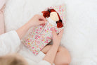 Child with doll in floral sleeping bag.