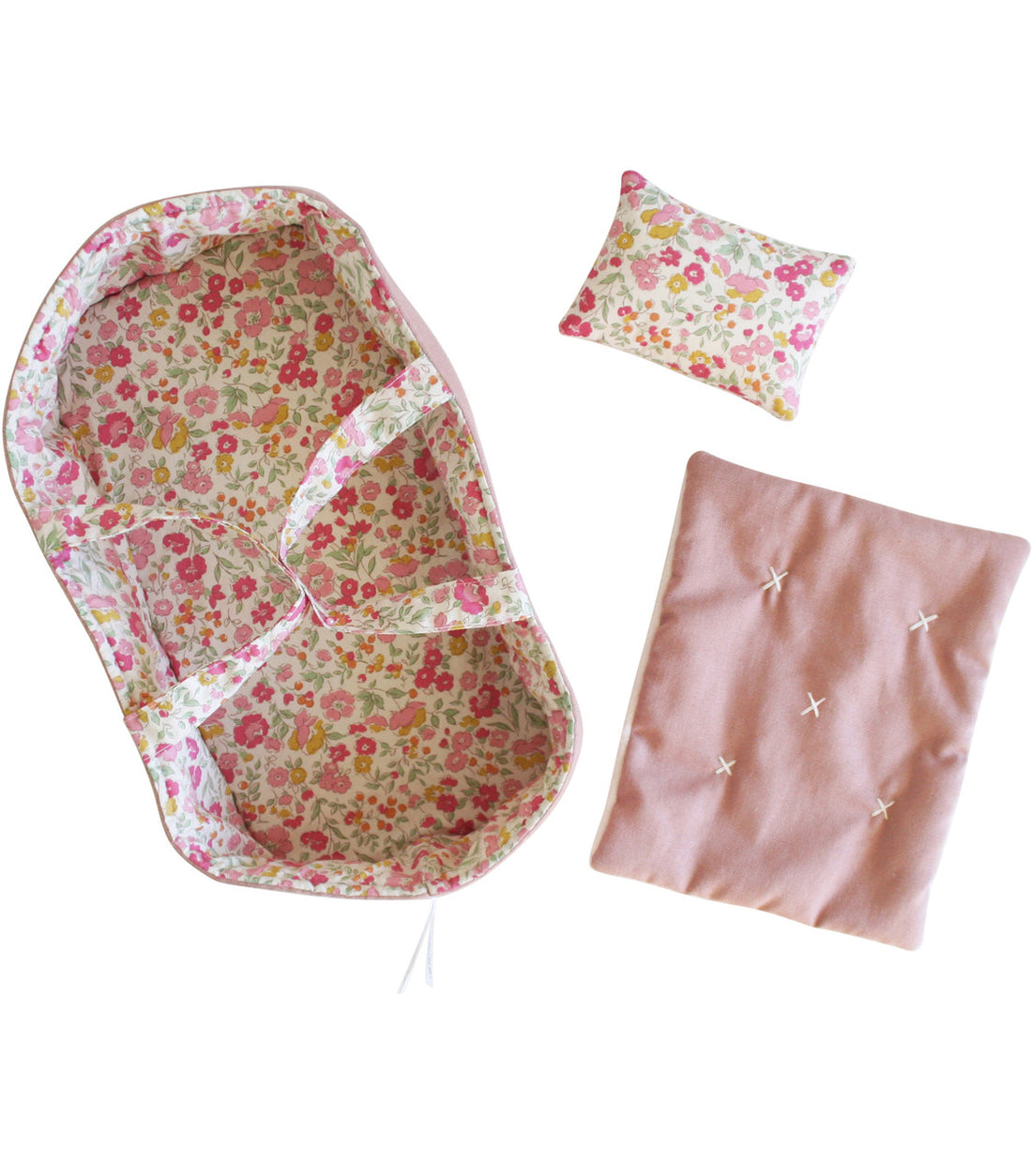 Doll bed with floral pattern, pillow, and pink blanket with white cross-stitches.