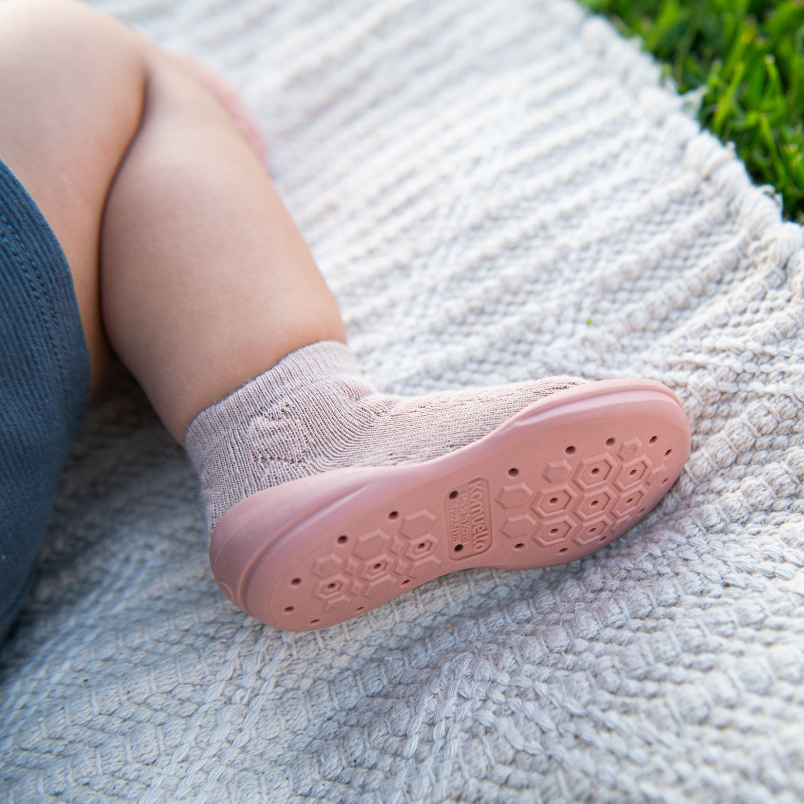 Baby foot wearing pink sock and shoe.