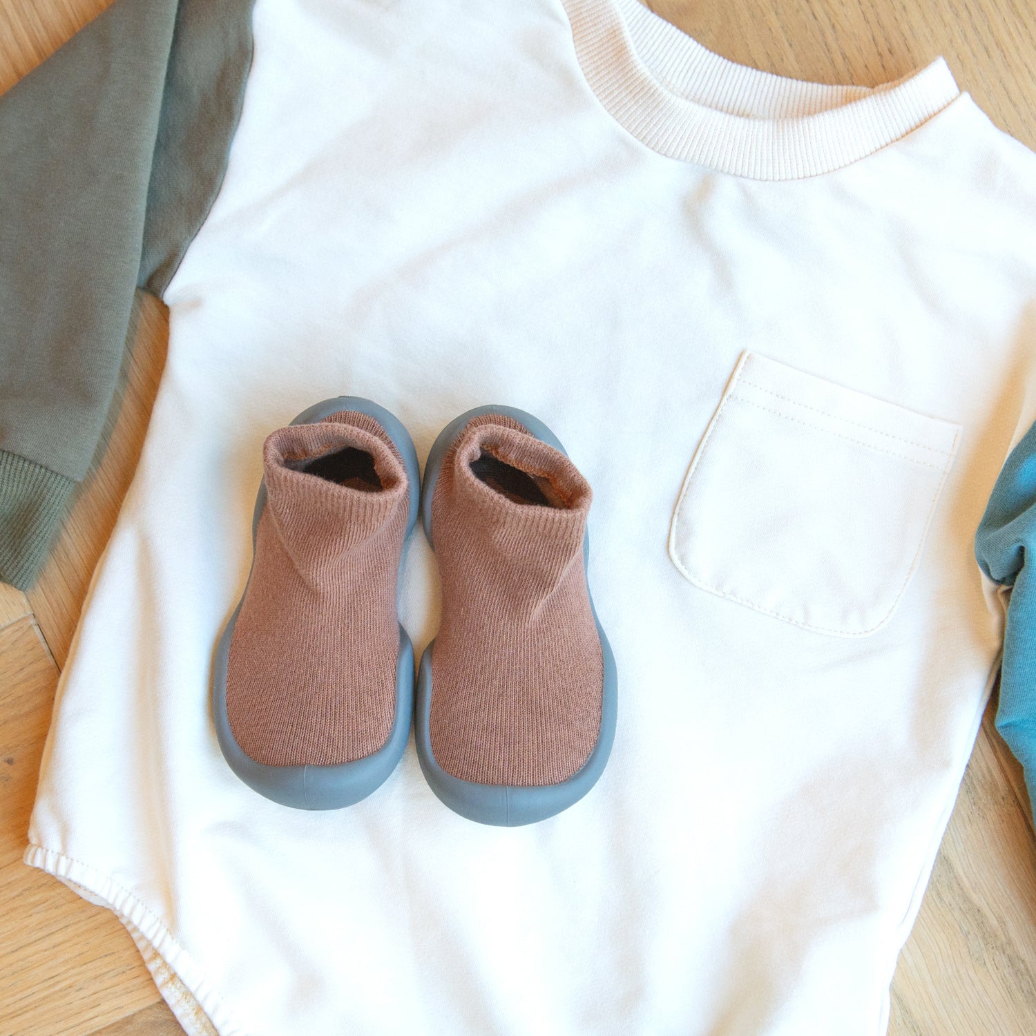 Baby onesie with color-blocked sleeves, paired with sock shoes.