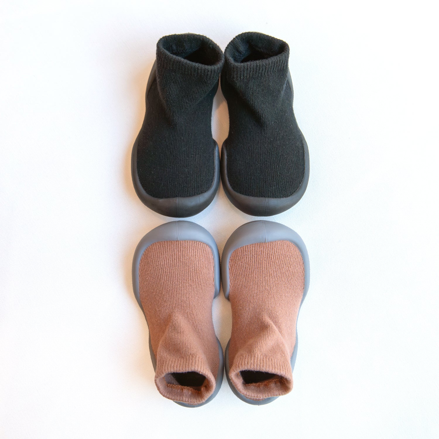 Two pairs of baby shoe socks, one black and one peach.