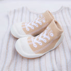 Tan baby sock-shoes on striped sweater.
