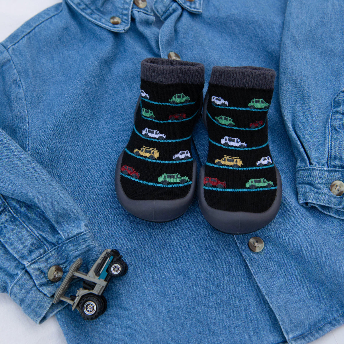 Denim shirt with car-patterned sock-shoes and toy truck.