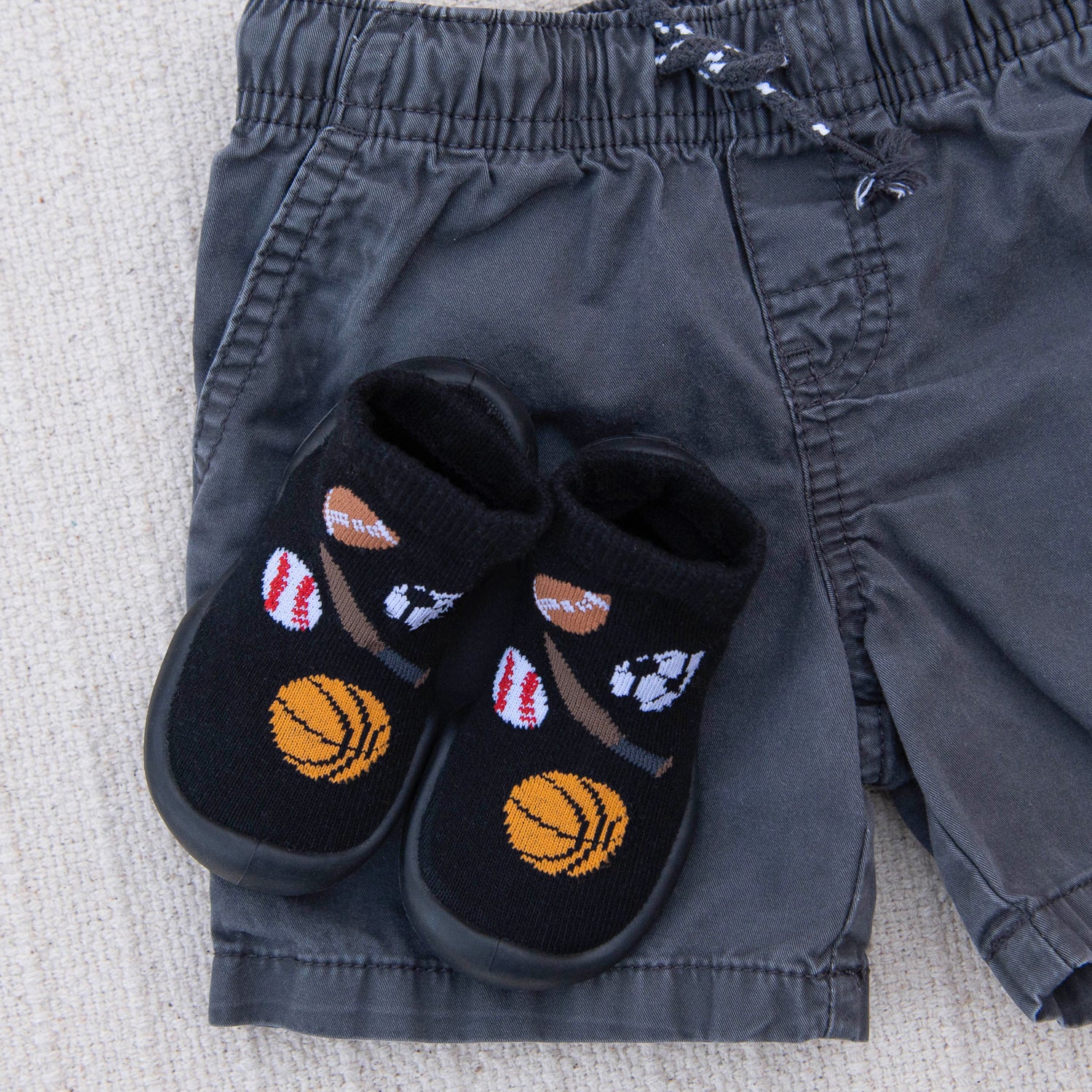 Black slippers with sports-themed designs on a gray fabric surface