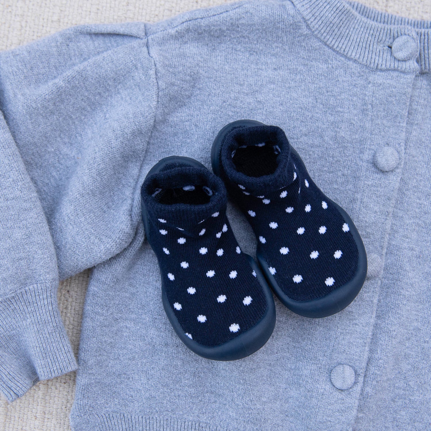 Navy baby boots with white polka dots on a gray sweater