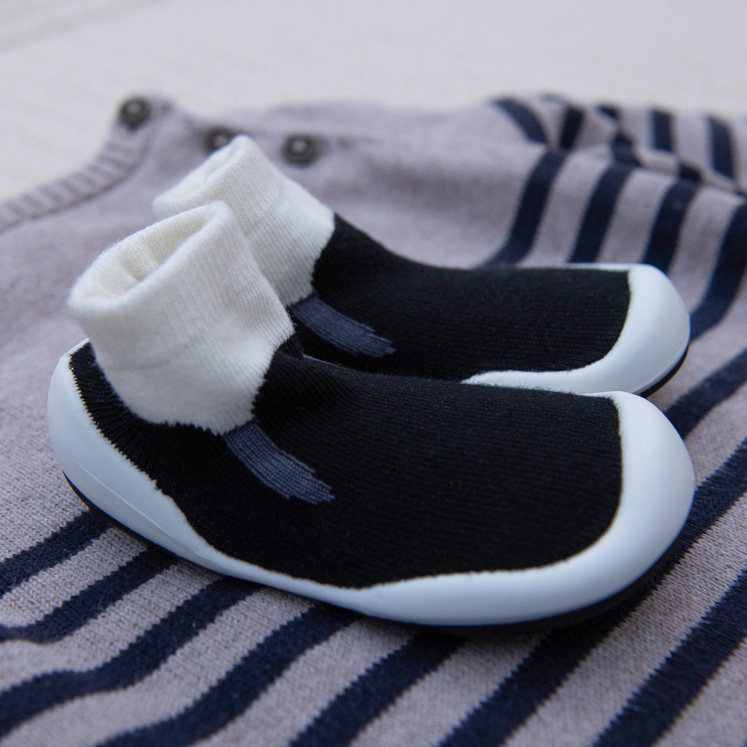 Black and white baby shoes on a striped fabric background