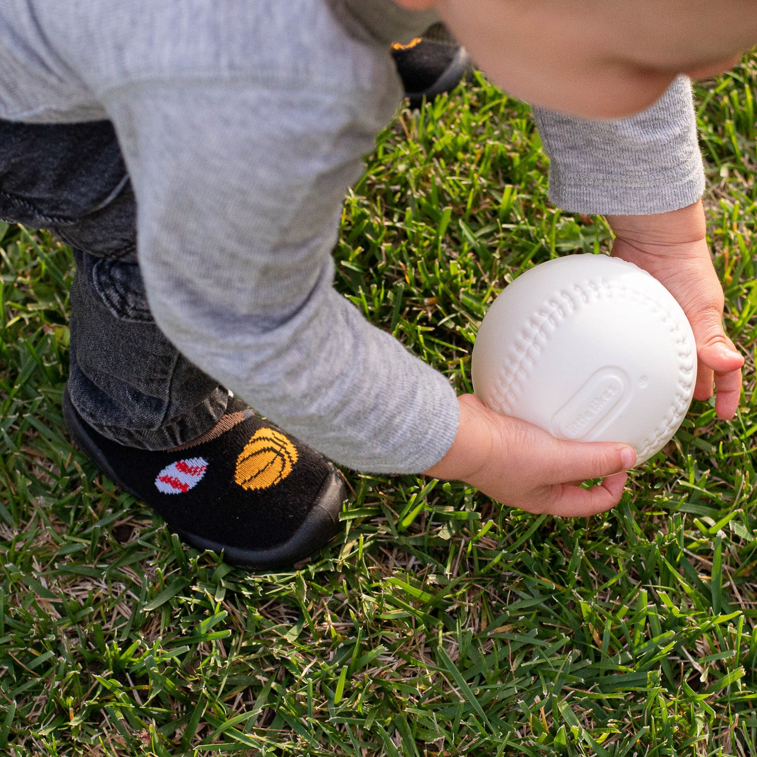 Child holding a white ball on grass