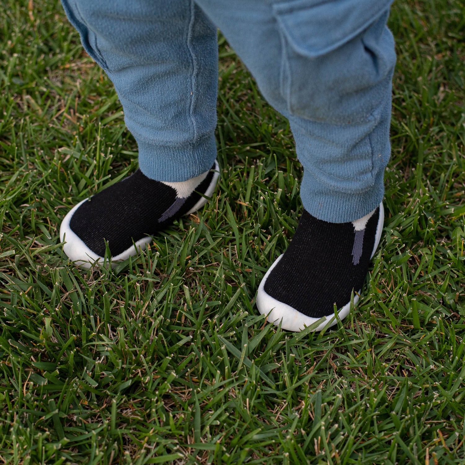 Person wearing black shoes with white soles on grass