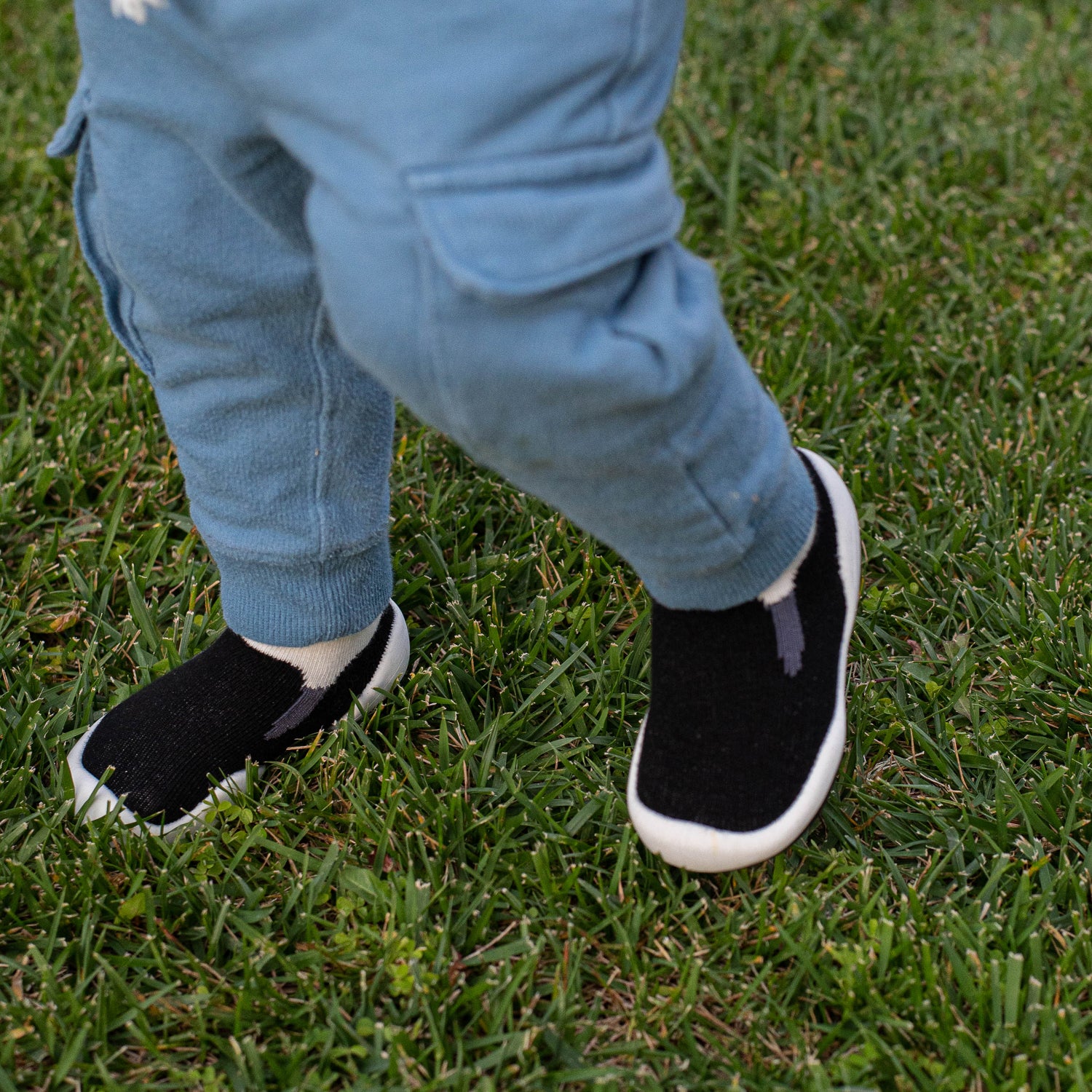 Child wearing black shoes with white soles on grass