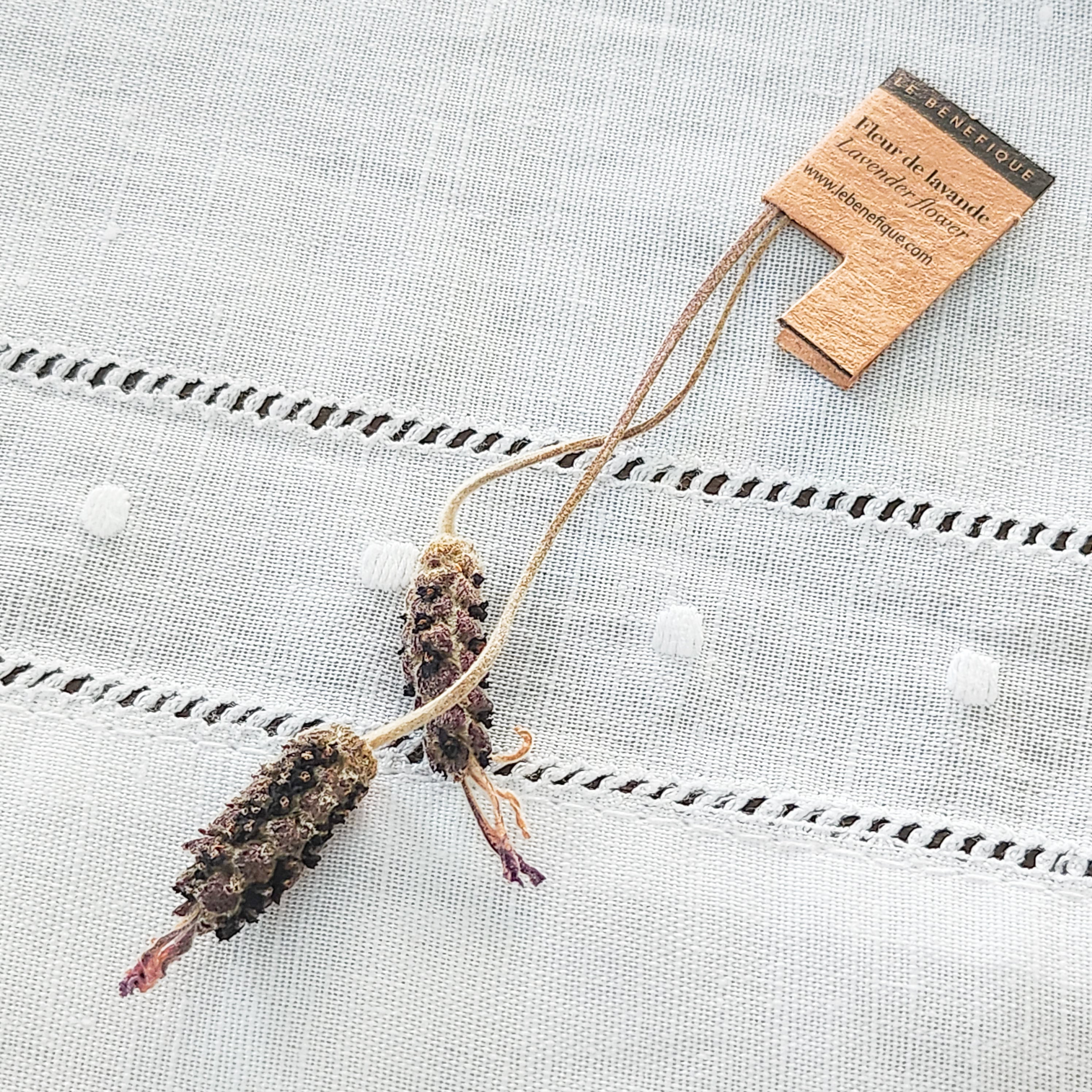 Dried lavender sprigs with a tag on textured white fabric.