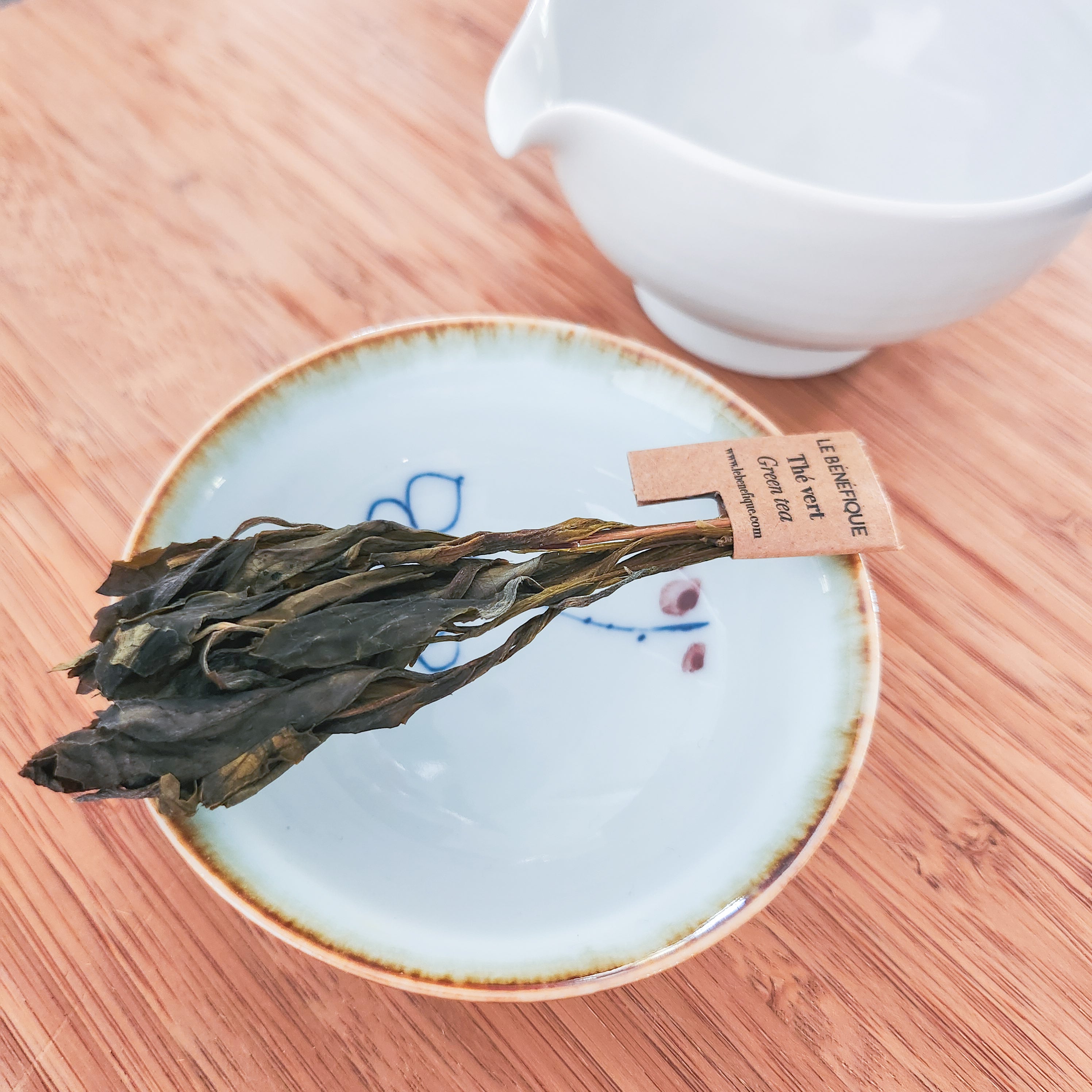 Dried tea leaves on a plate next to a white creamer.