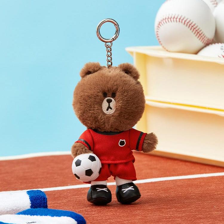 Brown teddy bear keychain in red soccer uniform holding a soccer ball.