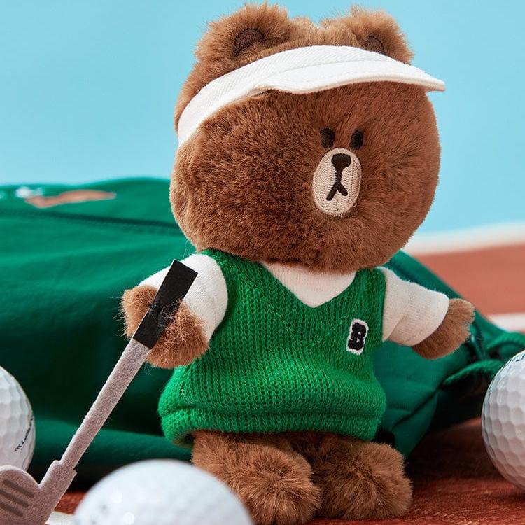 Brown bear plush toy in a green sweater vest with a white visor holding a golf club.