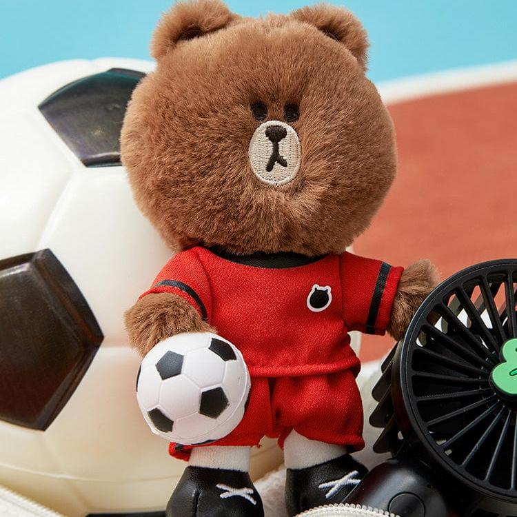 Stuffed bear in soccer uniform holding a small soccer ball.