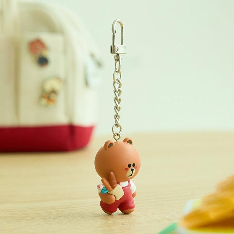 Brown bear keychain in red overalls with silver chain.
