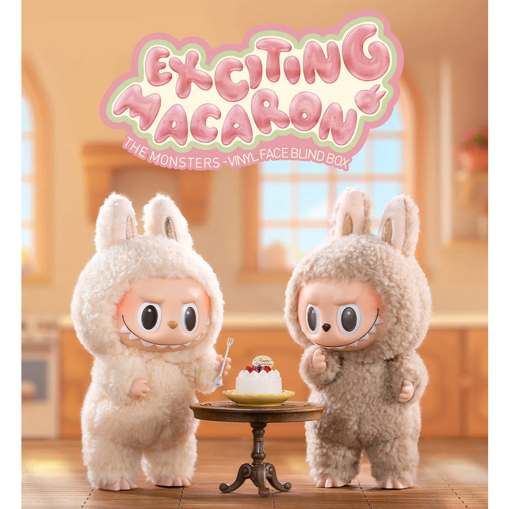 Two furry, rabbit-eared monster dolls stand beside a miniature cake in a kitchen setting. Above them is a logo reading, "Exciting Macaron."