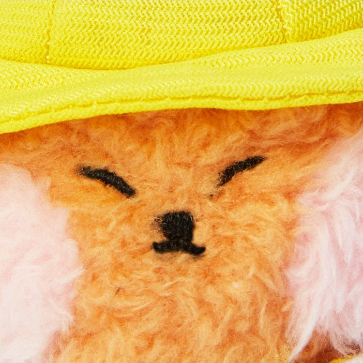 Close-up of an orange stuffed animal with pink cheeks wearing a yellow hat.