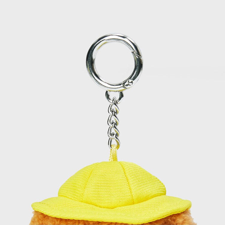 Close-up of a teddy bear keychain with a yellow hat and silver hardware.