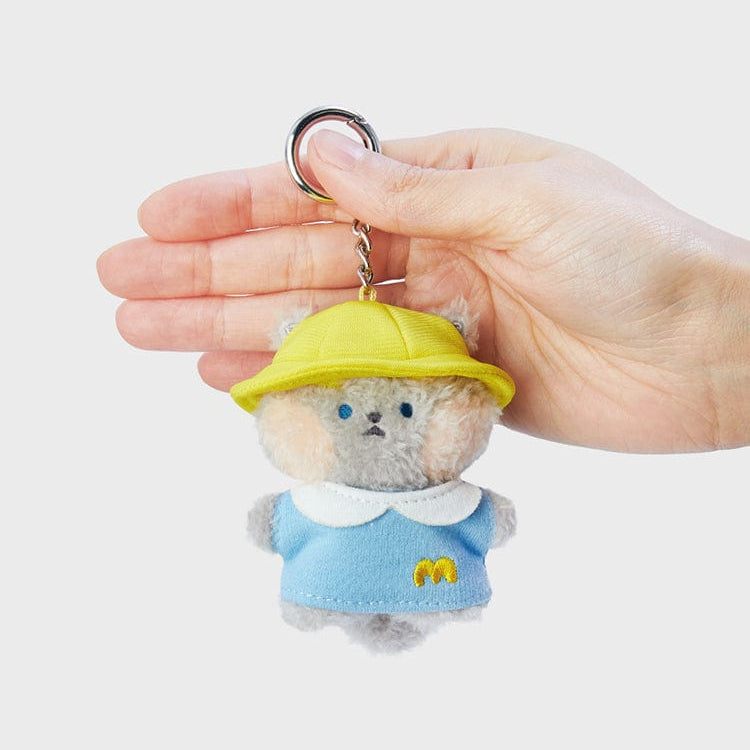 Gray plush teddy bear keychain with yellow hat and blue outfit.