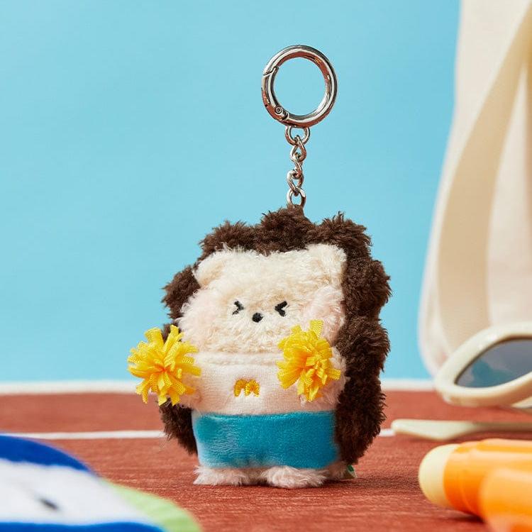 A fuzzy hedgehog keychain wearing a blue skirt and holding yellow pom poms.