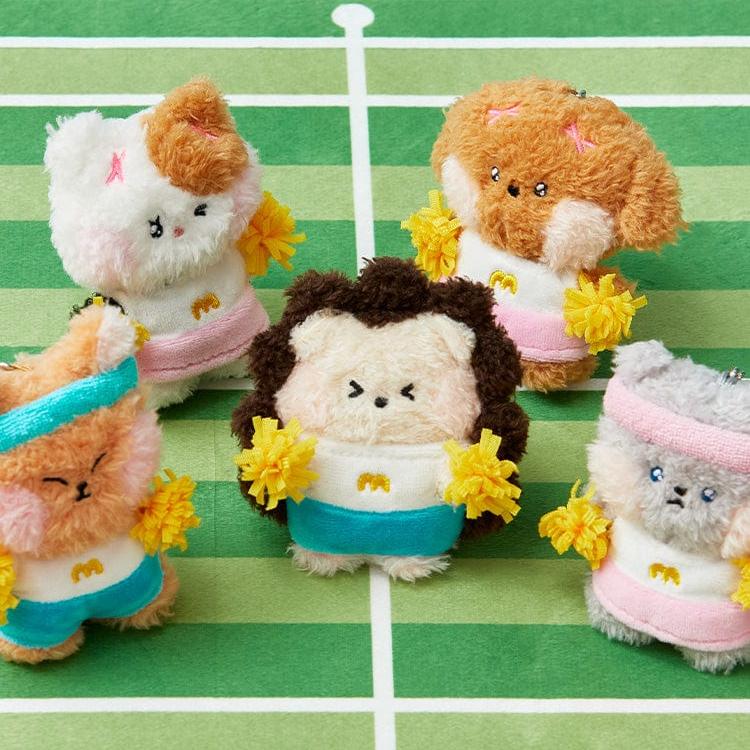 Five plush toys dressed as cheerleaders on a green and white striped background.