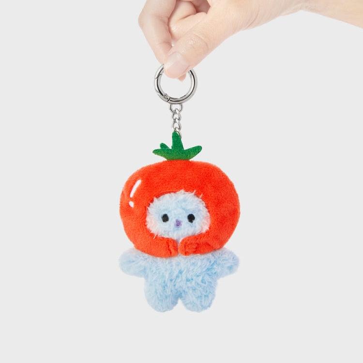 A hand holds a key chain featuring a blue plush character wearing a tomato costume.