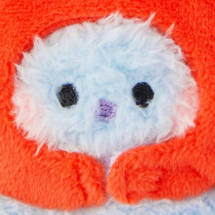 Close-up of a blue and white fuzzy creature with black eyes wearing an orange hood.