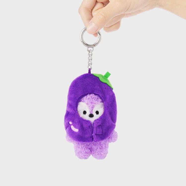 A hand holds a plush keychain of a cartoon animal dressed in a purple eggplant costume.