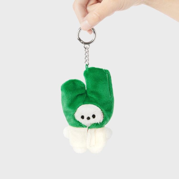 A hand holds a green and white plush keychain.