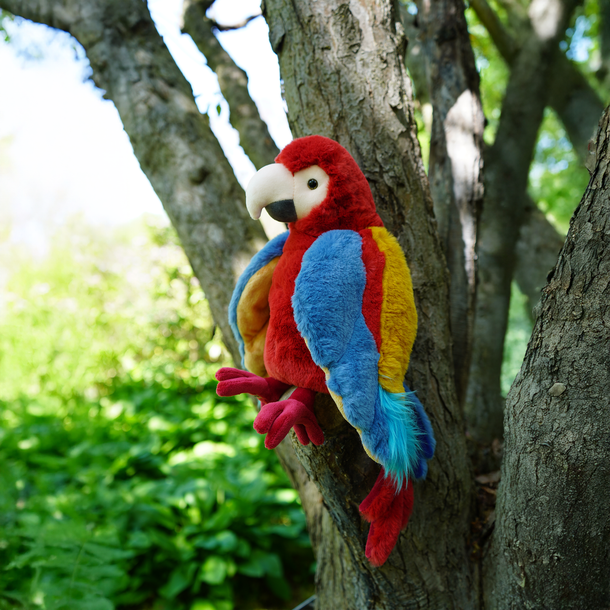 Colorful stuffed parrot toy perched on a tree branch with a natural background