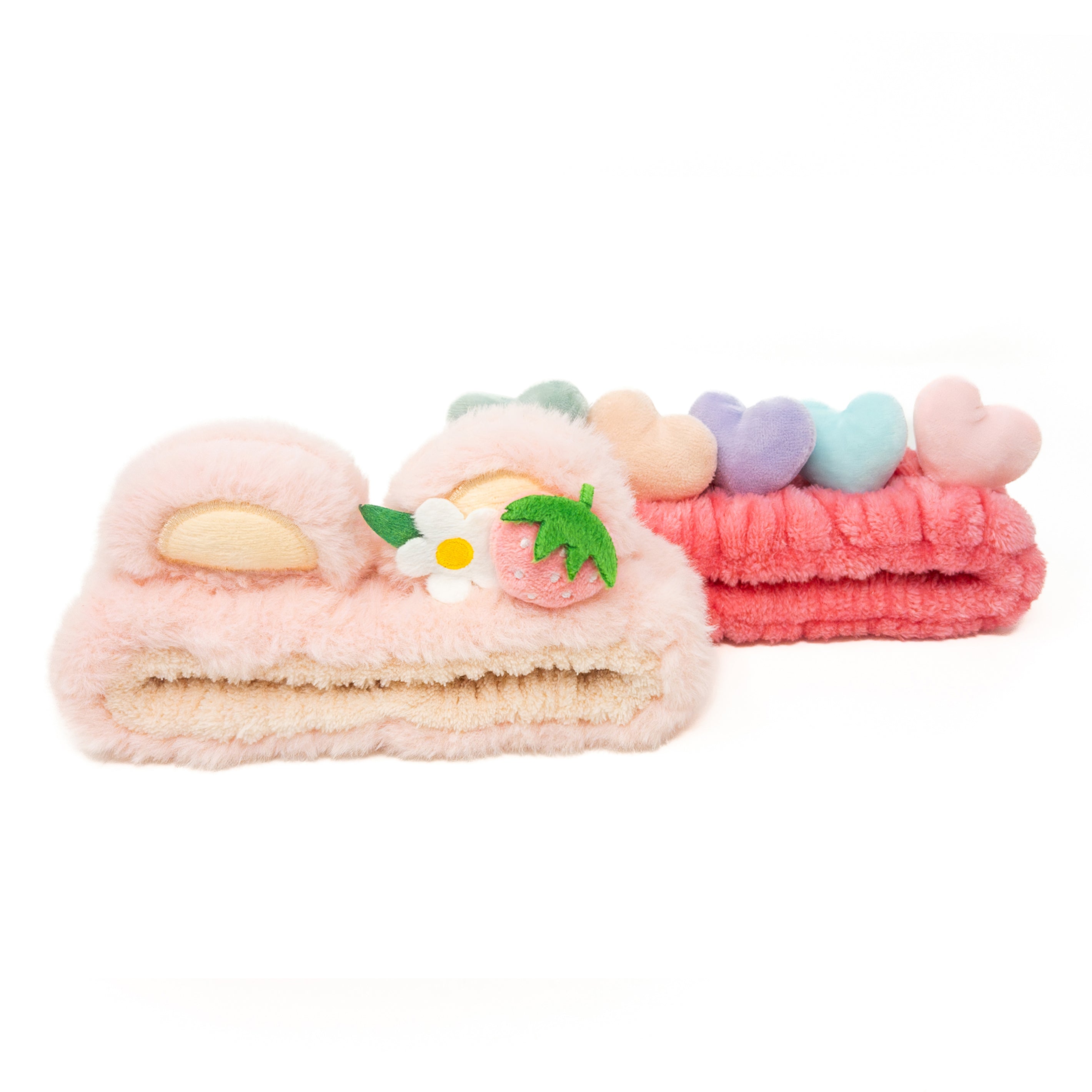 Two fuzzy headbands, one pink with heart decorations and one with a strawberry and flower.