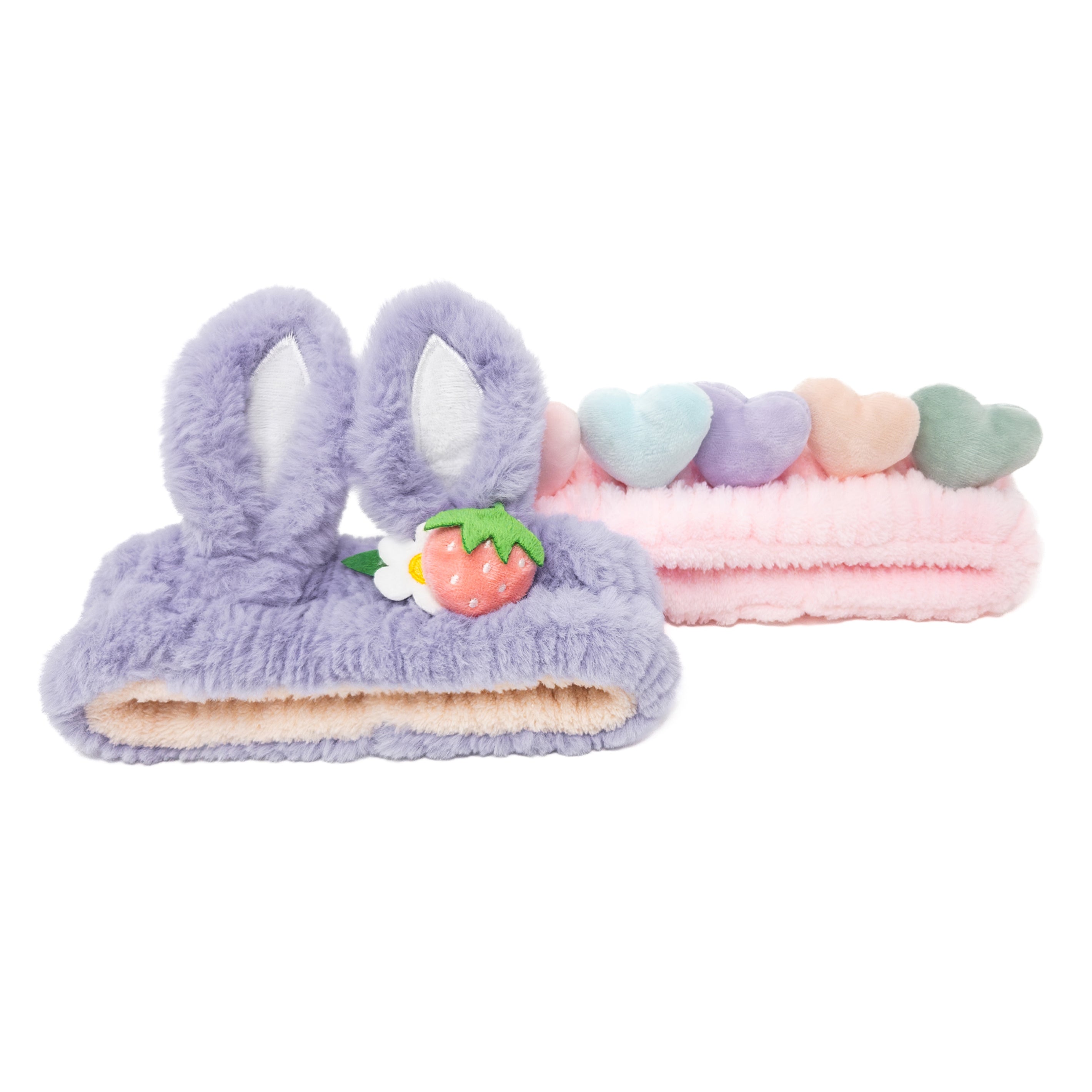 Two plush headbands. One is lavender with rabbit ears and a strawberry. The second one is pink with pastel-colored hearts.