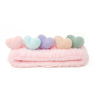 Pink plush headband with five pastel heart accents.